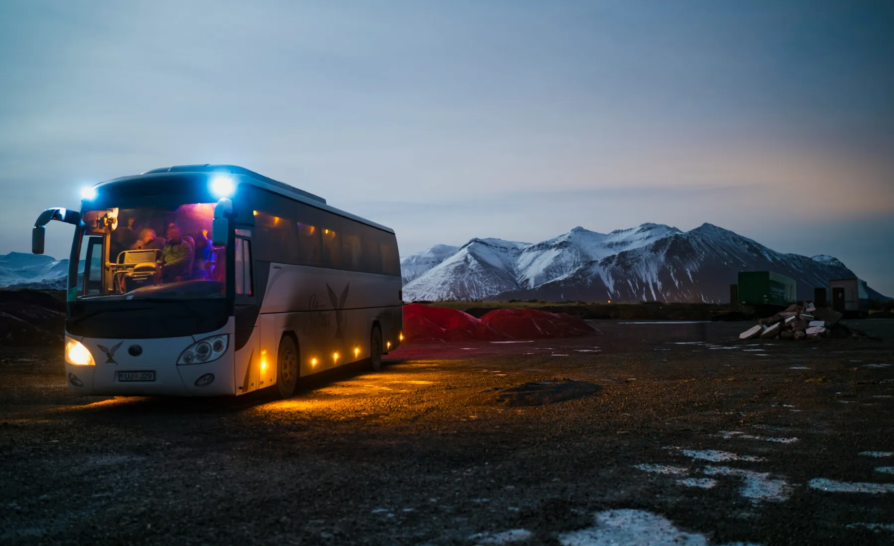 A RouteLine coach at dusk with its lights on